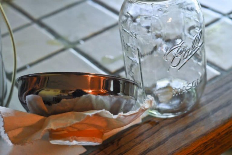 glass jar and metal bucket next to table