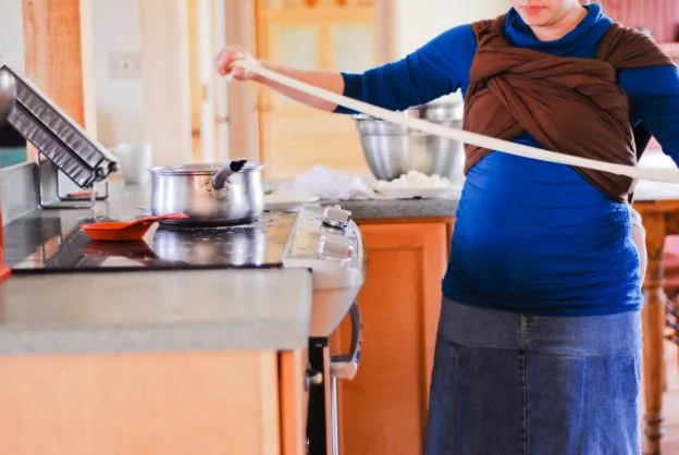 lady carrying child in kitchen stretching cheese