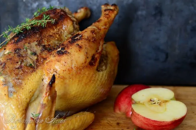 Apple-Honey-Stuffed-Chicken- whole on wood table next to apple slice