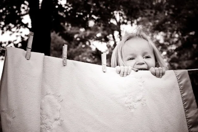 young girl standing behind sheet on the clothesline