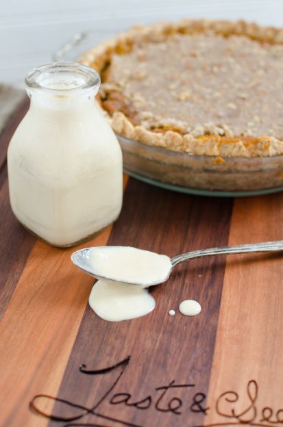 A jar of condensed milk beside a spoon and a pie