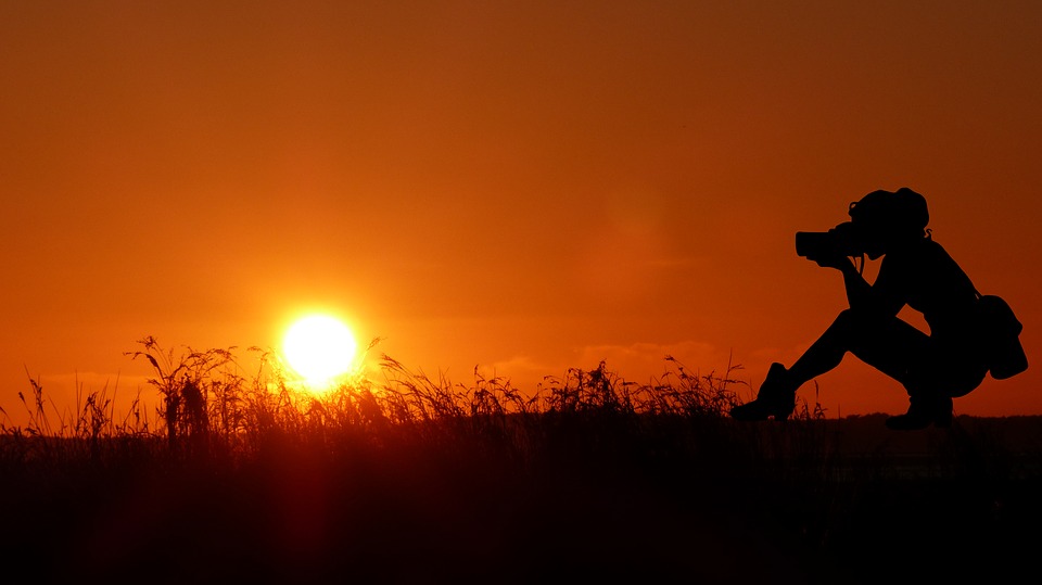 Silhouette of a woman photographing the sunset