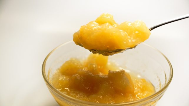 A bowl and spoon full of applesauce
