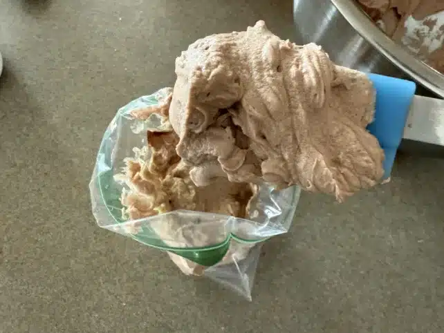 scooping chocolate protein ice cream mixture into a piping bag